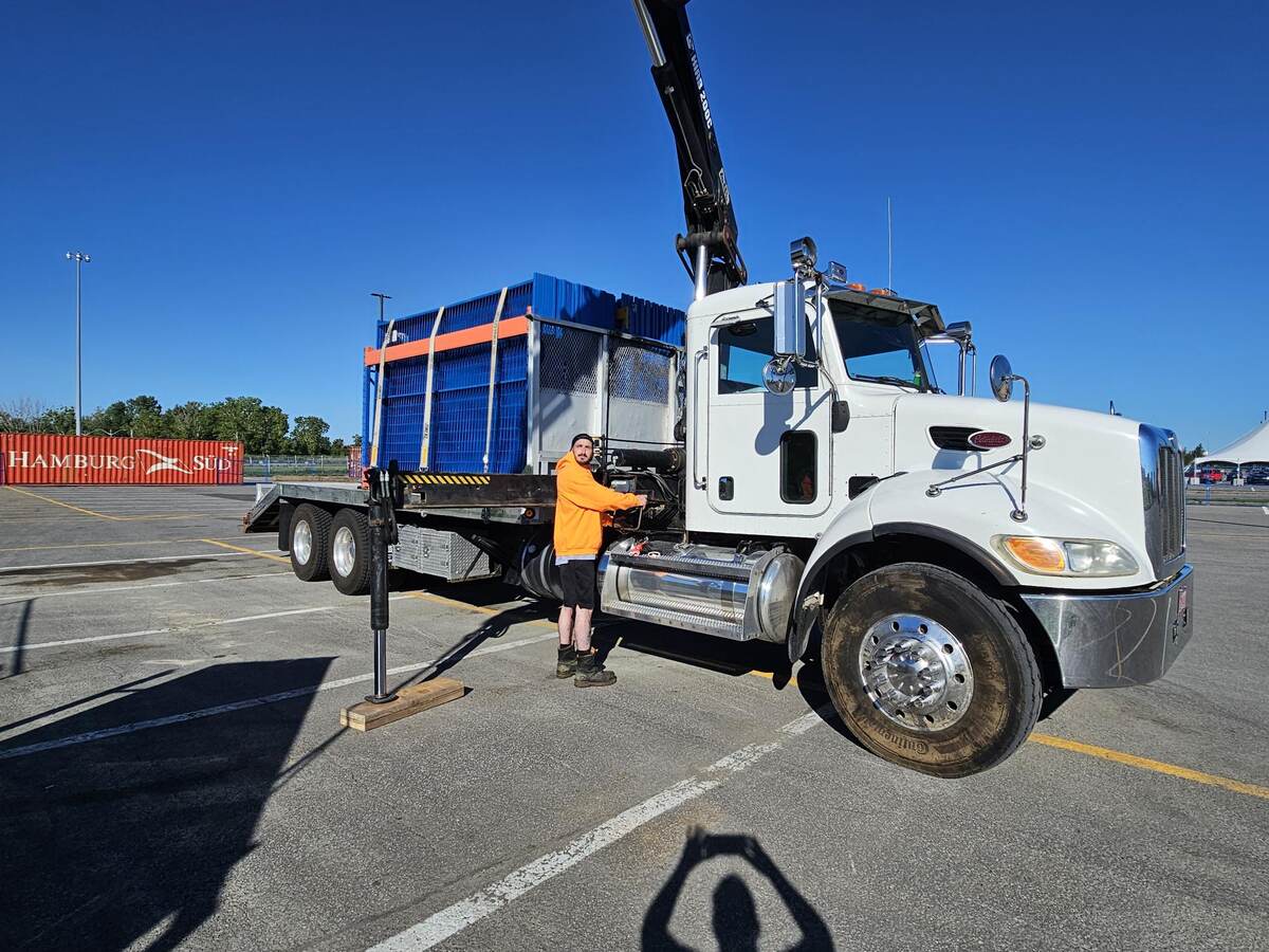 Opérateur de Clôtures de chantier Carrière devant un camion-grue blanc chargé de panneaux de clôture bleus